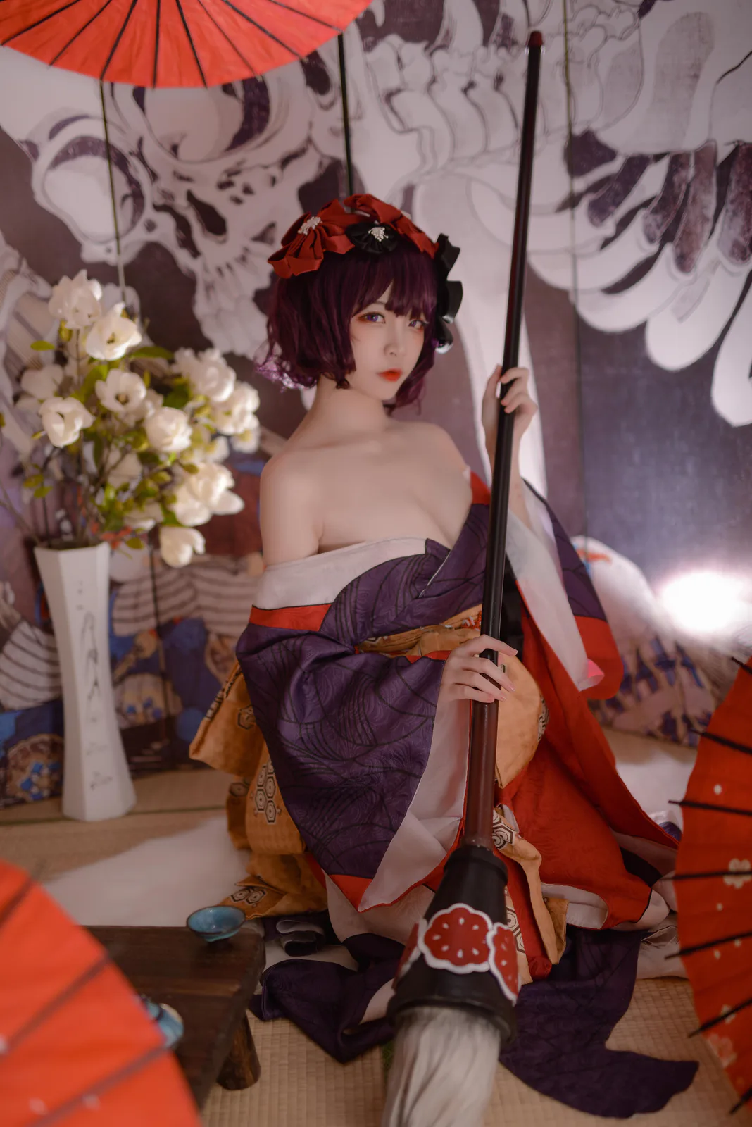 二佐穿紫红宽袖衣装双手上下握长笔,笔头朝画面下缘,身后有图案屏风与红伞 二佐穿紫红宽袖衣装双手上下握长笔,笔头朝画面下缘,身后有图案屏风与红伞